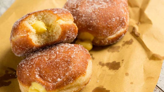 3 bolas de berlim com creme em papel pardo