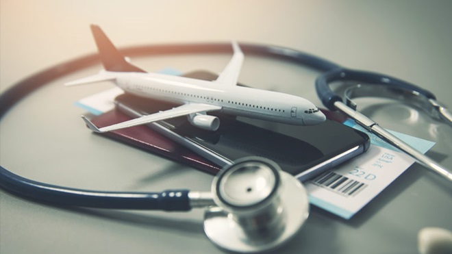 Miniatura de avião e passaporte em cima de uma mesa com estetoscópio à volta