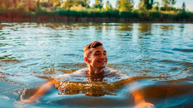 Jovem adulto a nadar na água de um rio