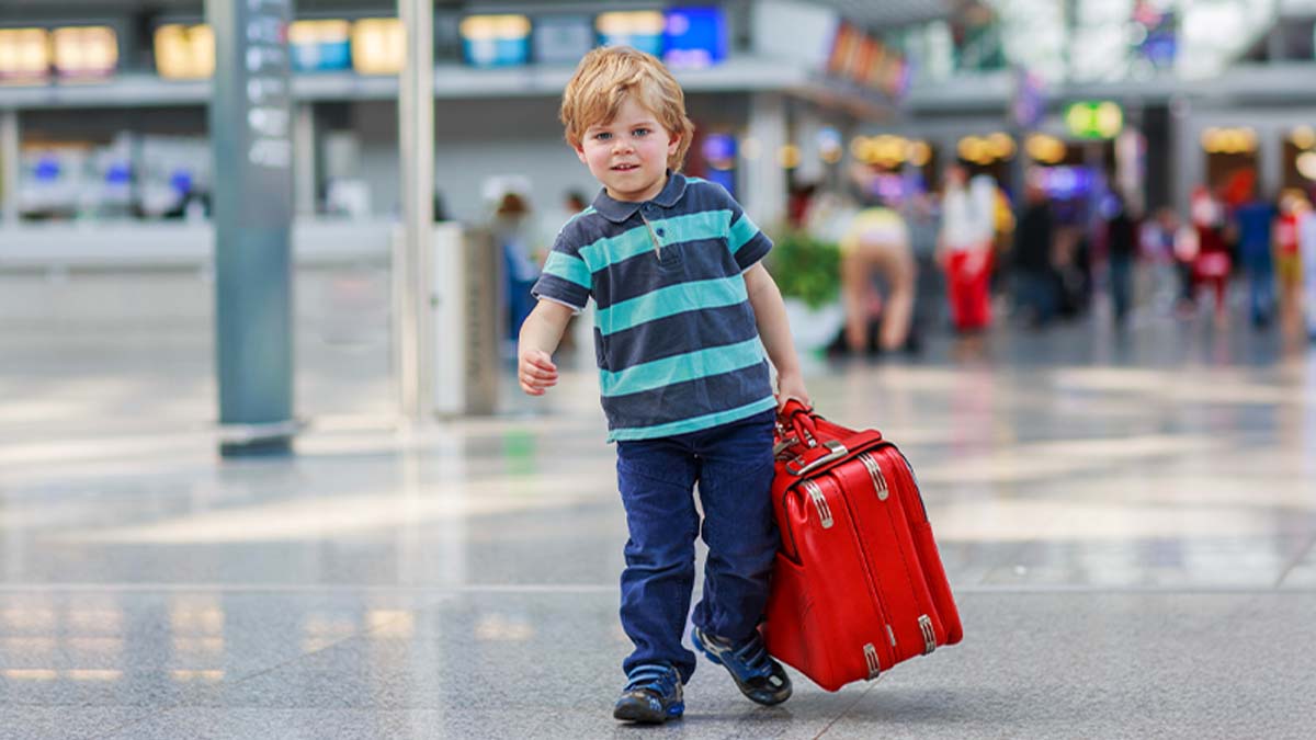 Criança no aeroporto a partir em viagem com uma mala