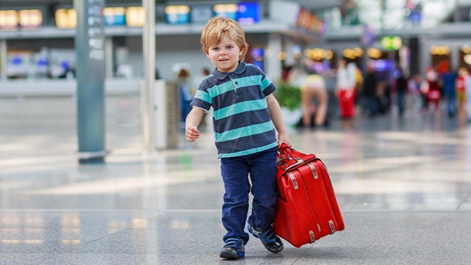 Criança no aeroporto a partir em viagem com uma mala
