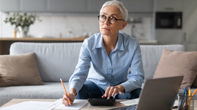 Mulher pensativa sentada em frente ao portátil