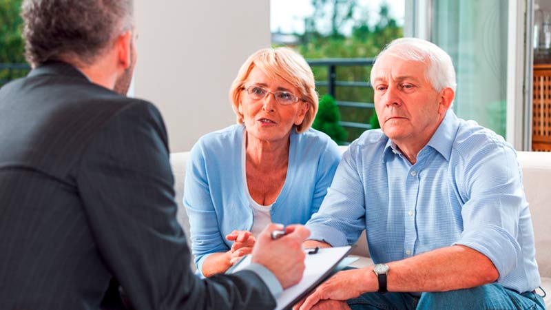 Casal sénior a aconselhar-se com um advogado, sentados numa sala