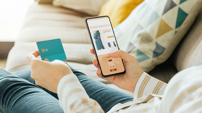 Grande plano de mão de mulher sentada no sofá a fazer compras online no telefone