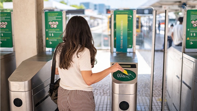 Mulher a passar o título de transporte nas portas de acesso ao transporte público
