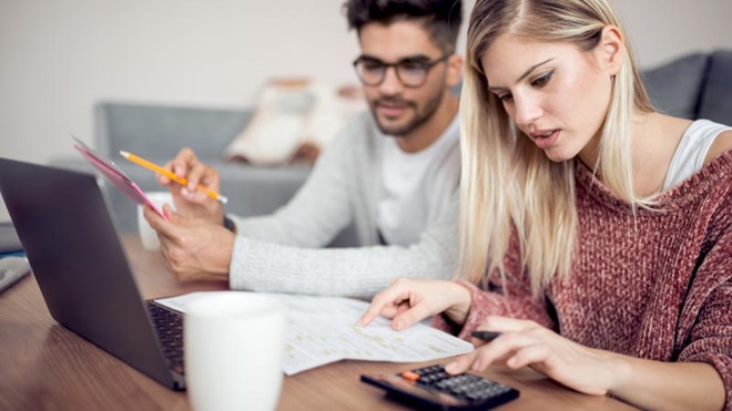 casal no portatil a fazer contas na calculadora