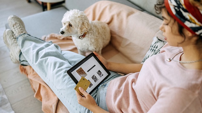 Rapariga deitada no sofá a fazer compras na internet