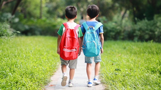 duas crianças com mochilas a irem para a escola sozinhas 