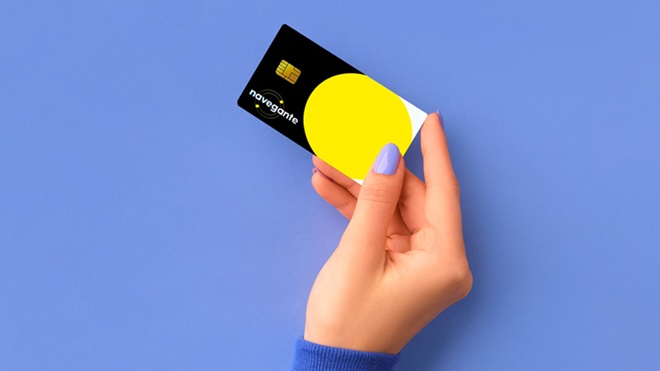 Grande plano de jovem com as unhas pintadas de roxo e manga da camisola roxa, a segurar um cartão Navegante, num fundo roxo