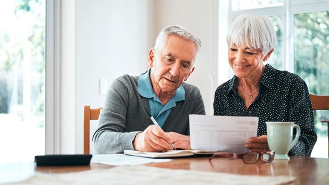 Casal sénior a tratar de documentos sentados a uma mesa numa sala