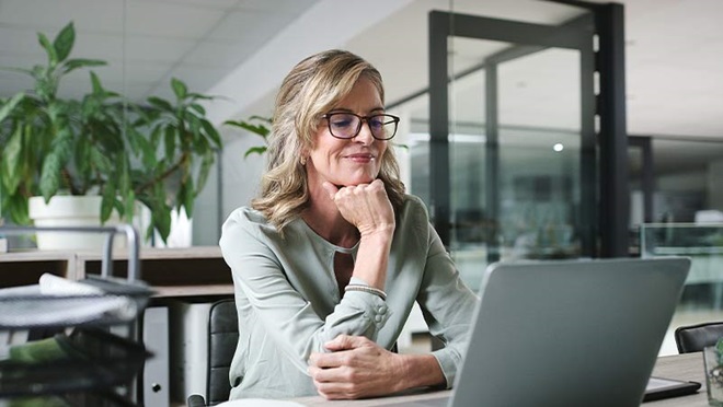 Mulher adulta sentada num escritório ao portátil