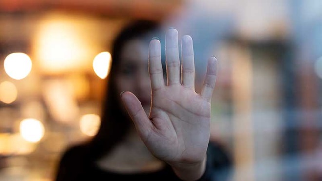 Mulher com a palma da mão encostada a um vidro