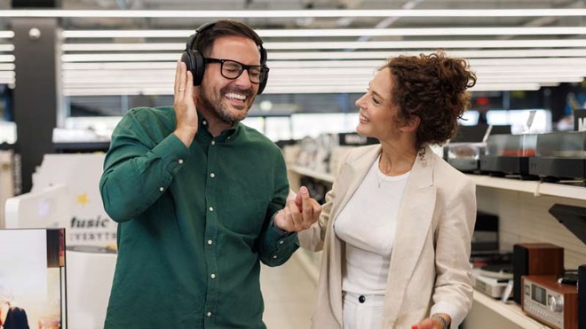 Casal a comprar aparelhos de som numa loja de grandes dimensões, tipo Worten