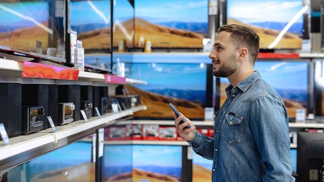Homem em loja de eletrodomésticos a escolher televisor
