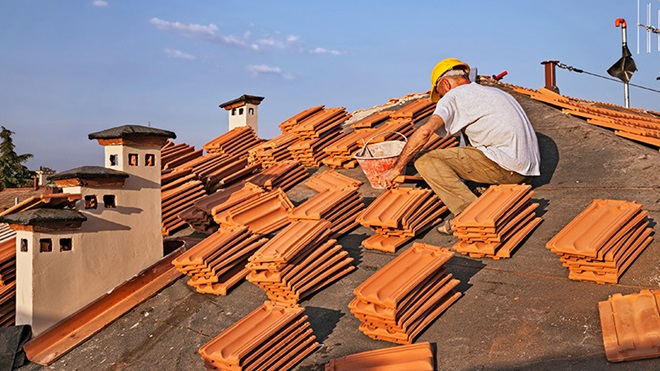 Homem a colocar telhas