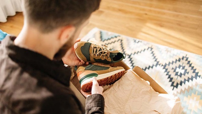 Homem a desempacotar encomenda de sapatos desportivos, sapatilhas