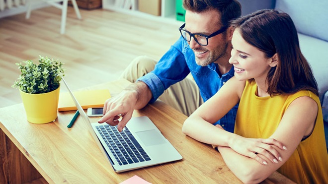 Casal em frente a um portátil pousado numa secretária