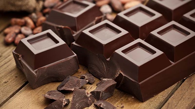 Tablete de chocolate grande partida sobre uma mesa de madeira