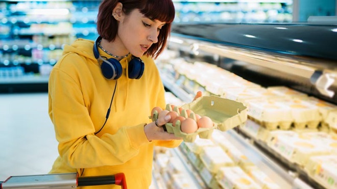Jovem mulher num supermercado a comprar ovos
