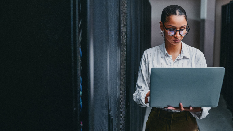 Mulher de pé com o portátil na mão a fazer a gestão de informação da área pessoal de subscritora.