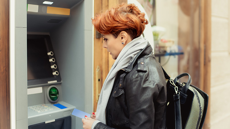 Mulher a fazer uma transferência bancária num caixa ATM