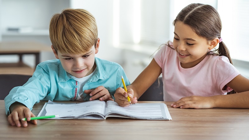 crianças a estudarem com um livro escolar