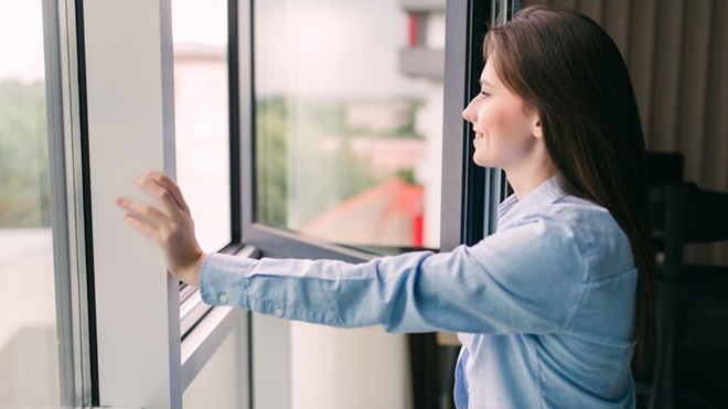 mulher a abrir a janela para refrescar a casa
