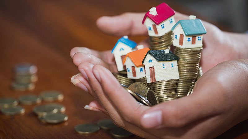 casas pequenas e moedas na mão de uma pessoa