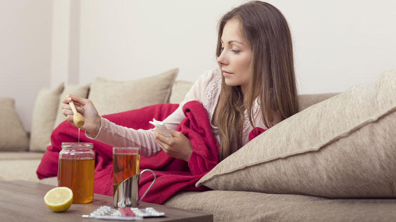 mulher em casa a tomar chá para a gripe