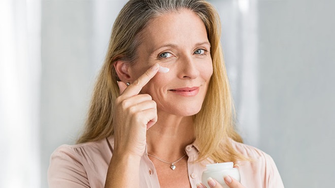 Mulher a aplicar creme antirrugas na zona das "patas de galinha"