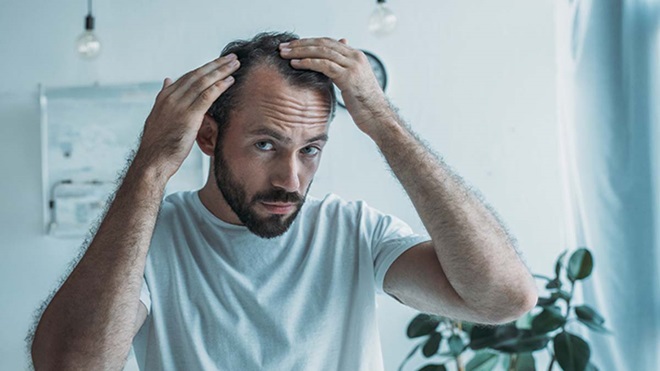 Homem a observar as entradas no cabelo