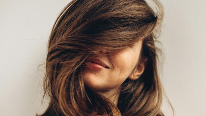 Grande plano de mulher com cabelo comprido e saudável a cobrir parte da cara