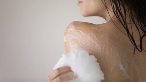Grande plano de mulher a tomar banho; com uma esponja aplica o gel de banho