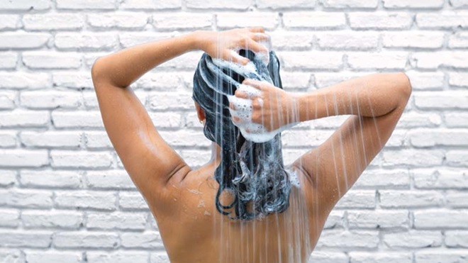 Mulher a tomar banho lava o cabelo comprido com champô