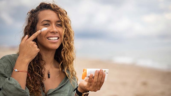 Mulher a colocar protetor solar na cara