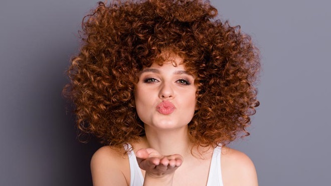 Mulher com cabelo encaracolado a mandar um beijinho