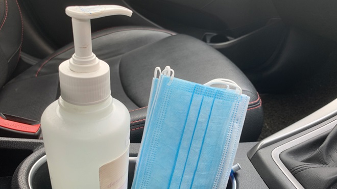 Uma embalagem de álcool-gel e uma máscara cirúrgica no interior de um carro