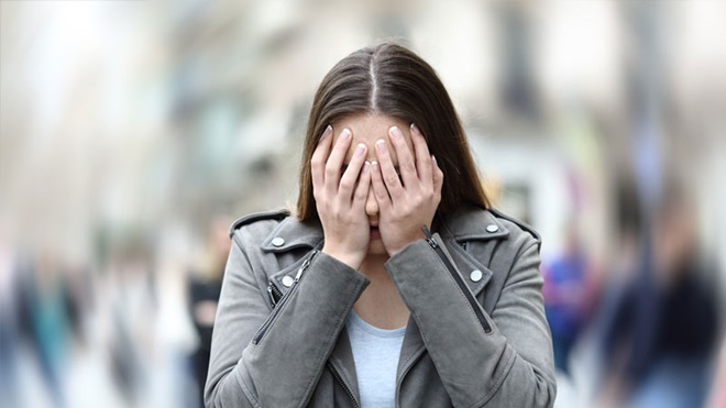 Mulher com as mãos na cara com aspeto angustiado