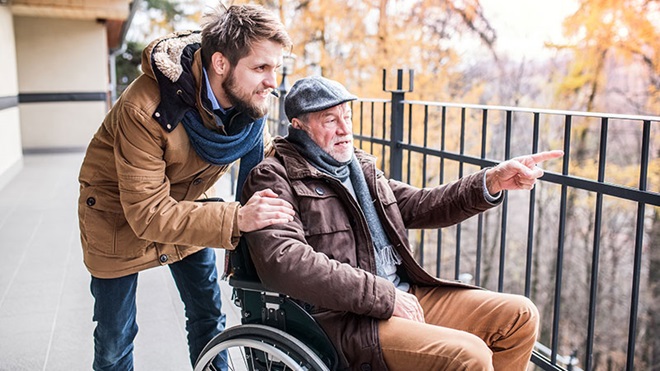 rapaz a empurrar homem numa cadeira de rodas