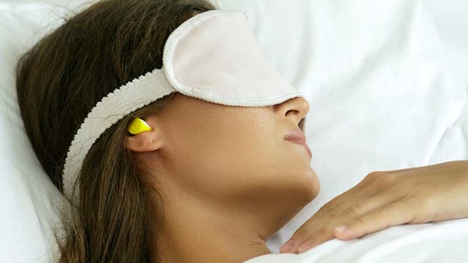 Mulher a dormir com tampões nos ouvidos e olhos tampados