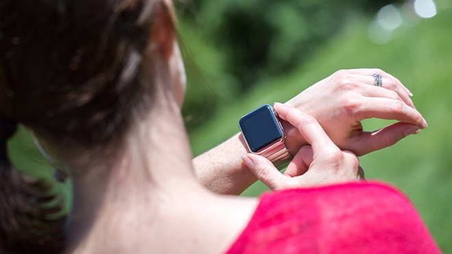 grande plano de mulher de costas a olhar para ecrã de smartwatch