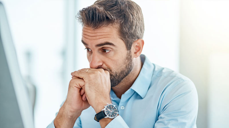 Homem com ar preocupado em frente a um portátil