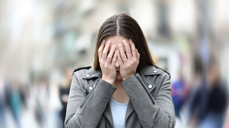 Mulher com as mãos na cara com aspeto angustiado