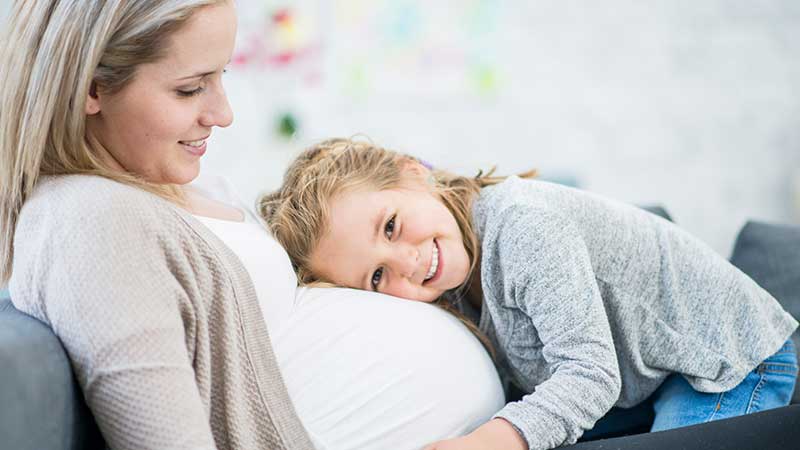 Mulher grávida com criança mais velha encostada à barriga