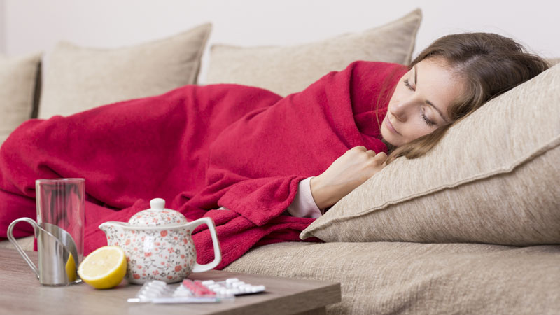 mulher deitada no sofá com constipação