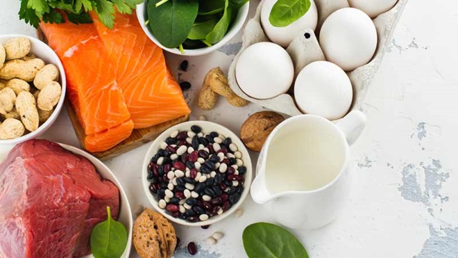 Alimentos crus em cima de uma mesa: ovos, carne vermelha, salmão e algumas verduras