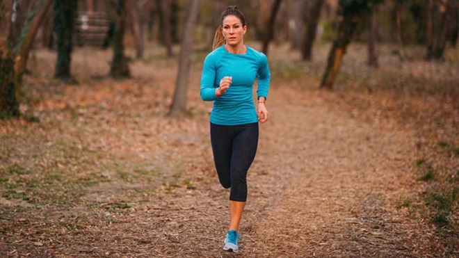 Mulher jovem com roupa desportiva a correr num parque no outono