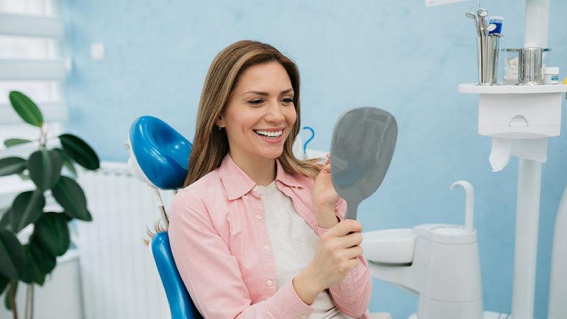 Mulher jovem a ver-se ao espelho no dentista