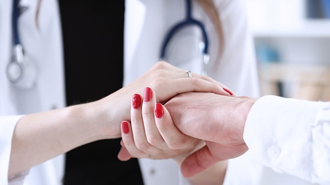 Médico a segurar a mão do paciente