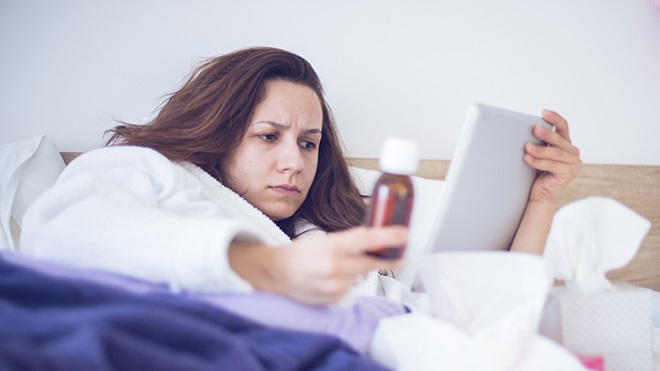 mulher na cama doente a aceder a serviços de saúde no tablet